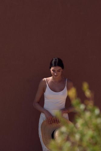 a woman in a white tank top holding a hat at Arcasa Villas Collection by Omilos Hotels in Archanes