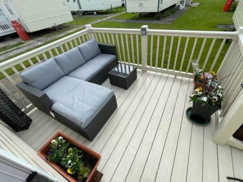 a couch sitting on a deck with two plants at Cala Gran Holiday Park - Holiday Accommodation 10830 in Fleetwood