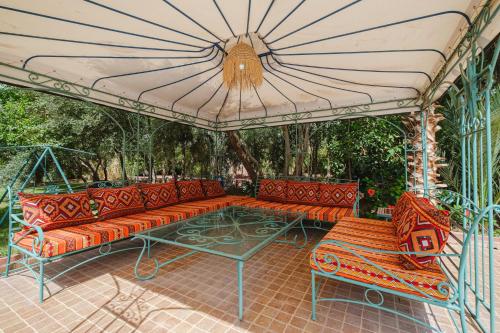 a patio with orange benches and a table and an umbrella at Dar Salah - Eddine Oasis Pool & SPA in Oulad Mazoug