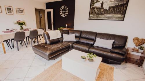 a living room with a leather couch and a table at La Loupiote - Jacuzzi compris SANS supplément ! in Lupcourt