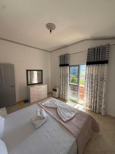a bedroom with a large white bed and a window at SunHome Ismailaj in Poliçan