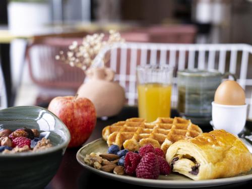 a table with a plate of waffles and fruit at ibis Styles Versailles Saint Quentin en Yvelines in Saint-Cyr-lʼÉcole