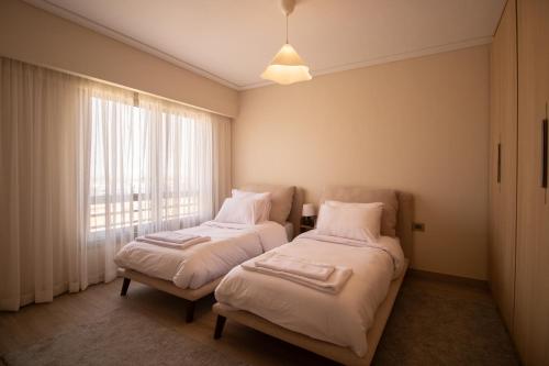 two beds in a room with a window at Luxury Rooms in the Heart of Pyramids in Kafr Ghaţāţī