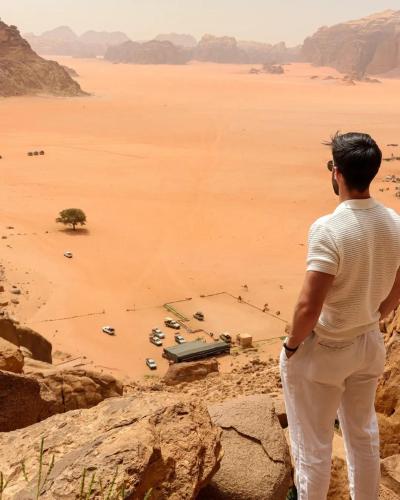 a man standing on top of a cliff looking at the desert at Ramses luxury rum camp in Wadi Rum