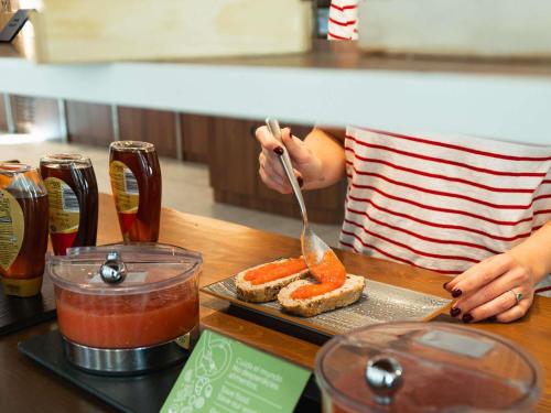 a person is eating a piece of bread with a spoon at Ibis Styles Sevilla City Santa Justa in Seville