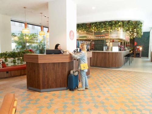 a woman standing at a counter in a shopping mall at Ibis Styles Sevilla City Santa Justa in Seville
