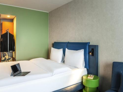 a bedroom with a large white bed with a blue headboard at ibis Styles St Margrethen Bodensee in Sankt Margrethen