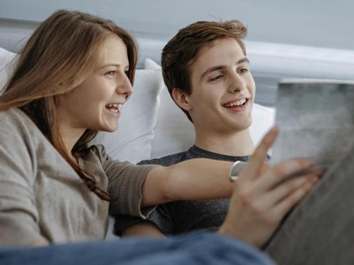 a man and woman sitting on a bed looking at a tablet at ibis Styles St Margrethen Bodensee in Sankt Margrethen