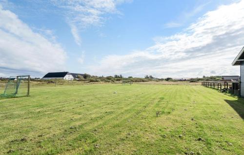 a large grass field with a house in the background at Awesome Home In Harboøre With Sauna in Langerhuse