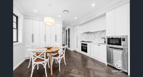 Marsden ParkにあるCouples haven - 2 bedroomsの白いキャビネット、木製テーブルと椅子付きのキッチンが備わります。