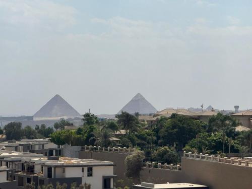 a view of the pyramids from a city with buildings at Luxury Rooms in the Heart of Pyramids in Kafr Ghaţāţī