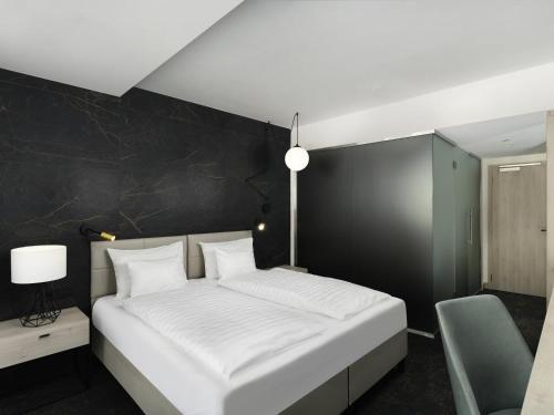 a bedroom with a white bed and a black wall at Mercure Tokaj Center in Tokaj