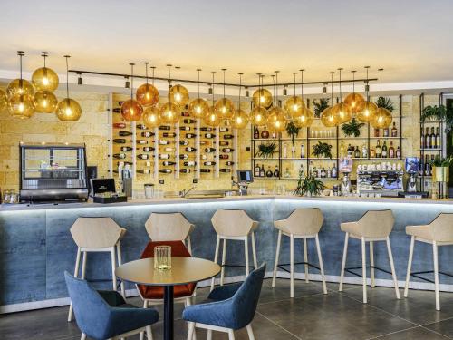 a restaurant with chairs and a bar with lights at Mercure Tokaj Center in Tokaj
