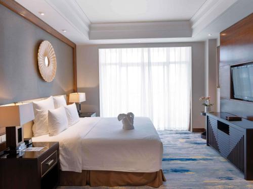 a hotel room with a bed and a television at Pullman Haikou in Haikou