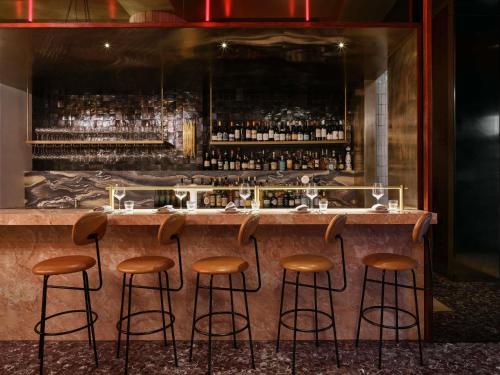 a bar with stools at a counter in a room at Hotel Morris Sydney, Handwritten Collection in Sydney