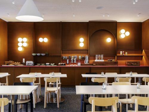 a dining room with white tables and chairs at ibis budget Münster City in Münster