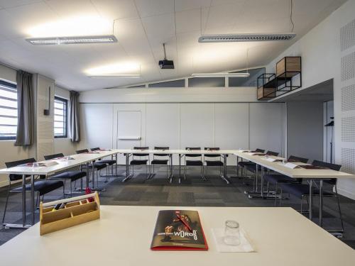 a classroom with tables and chairs and a book on a table at ibis Lyon Sud Oullins in Oullins