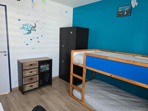 une chambre avec un lit superposé avec un mur bleu dans l'établissement Ti Goéland 4 chambres Proche Mont St Michel, à Roz-sur-Couesnon