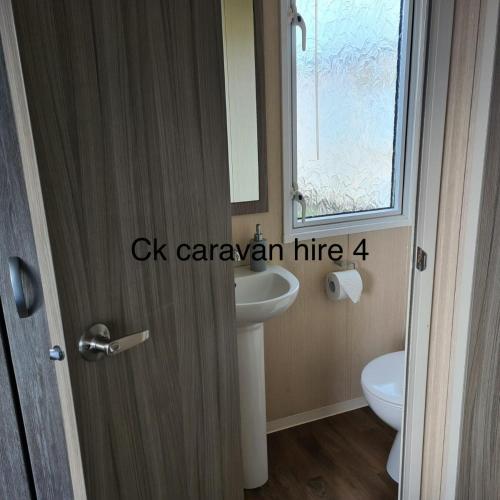a bathroom with a sink and a toilet and a mirror at Whitehouse Leisure Park - Holiday Accommodation 19057 in Kinmel Bay
