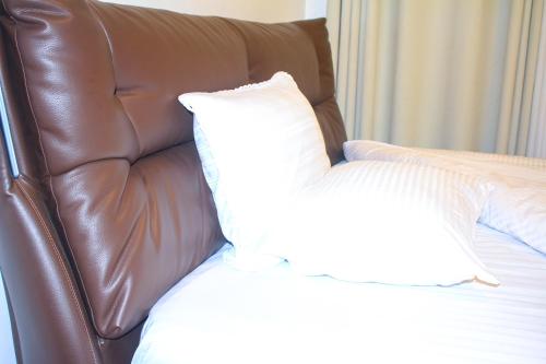a brown leather couch with a white pillow on a bed at Beach Side Apartment in Gisenyi