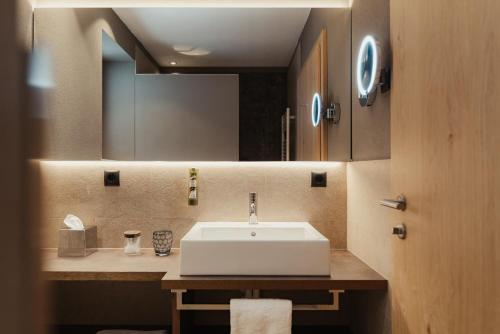 a bathroom with a white sink and a mirror at Hotel B&B Feldmessner in Brunico