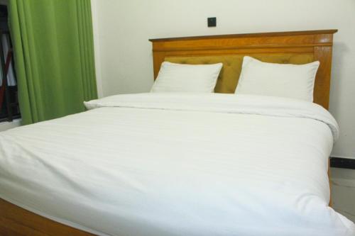 a bed with white sheets and a wooden headboard at Beach Side Apartment in Gisenyi