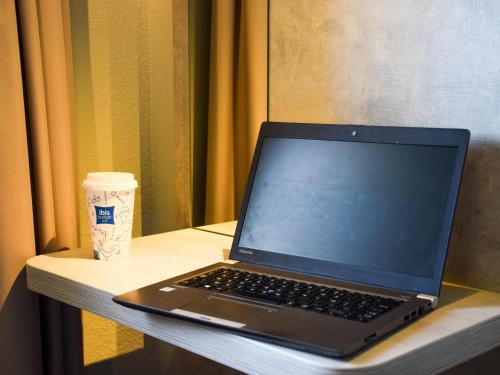 a laptop computer sitting on a table with a cup of coffee at ibis Budget Millau Viaduc in Millau