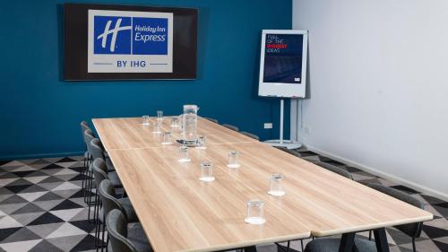 a conference room with a wooden table with glasses on it at Holiday Inn Express Burton on Trent by IHG in Burton upon Trent