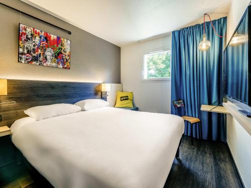 a hotel room with a large white bed and a window at Greet Hotel Bordeaux Floirac Arena in Floirac