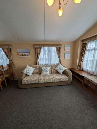 a living room with a couch in a room with windows at Camber Sands Holiday Park - Holiday Accommodation 21210 in Camber