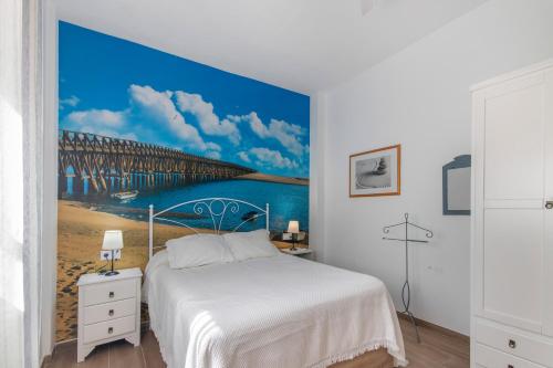 a bedroom with a large painting of a pier at Casa Alma in Isla Cristina