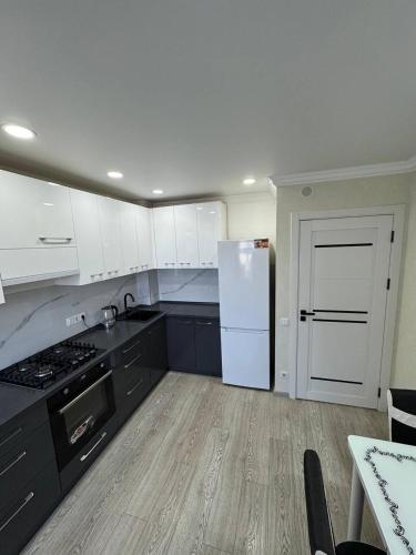 a kitchen with black cabinets and a white refrigerator at Panorama view apartament tolstoi str in Chişinău