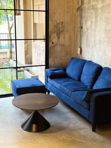 a living room with a blue couch and a table at The Arch Casa - Design Hotel Pai in Pai