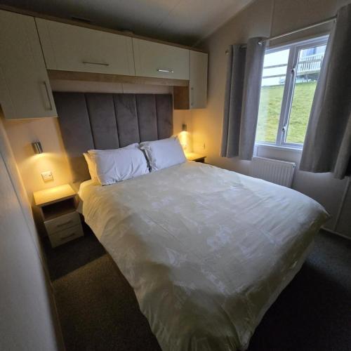 a bedroom with a large white bed with a window at Thornwick Bay Holiday Village - Holiday Accommodation 20633 in Flamborough