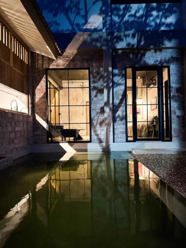 a house with a pool of water in front of windows at The Arch Casa - Design Hotel Pai in Pai