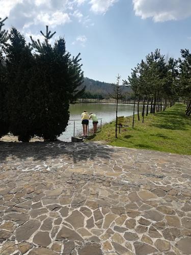 two people standing on a stone path near a body of water at Zacisze Nad Stawami 