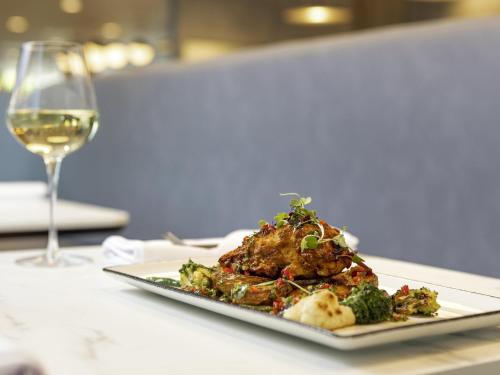 a plate of food on a table with a glass of wine at Novotel Liverpool Paddington Village in Liverpool