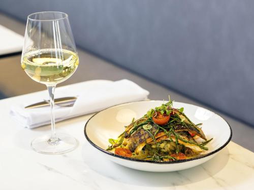 a plate of food and a glass of wine on a table at Novotel Liverpool Paddington Village in Liverpool