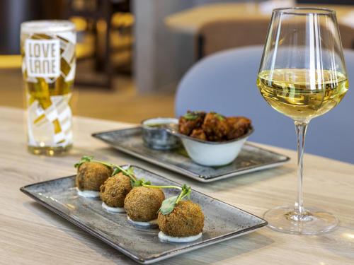a table with two plates of food and a glass of wine at Novotel Liverpool Paddington Village in Liverpool
