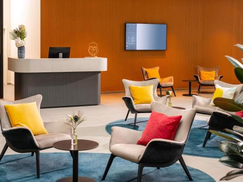 a waiting room with chairs and a reception counter at Mercure Geneva Airport in Geneva