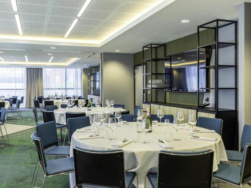 a restaurant with white tables and chairs and a room with windows at Novotel Liverpool Paddington Village in Liverpool