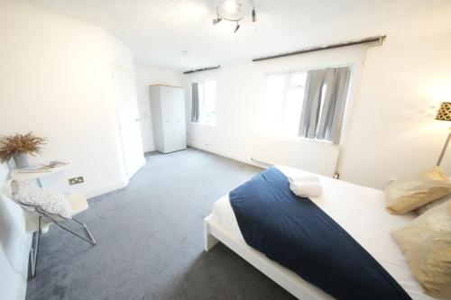 a white bedroom with a bed and a window at Airport Comfy Stay in Harmondsworth