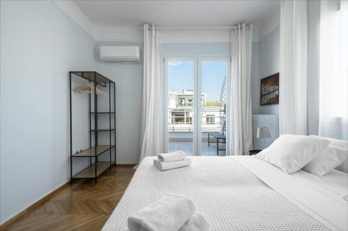 Un dormitorio blanco con una cama grande y una ventana. en Aristotelous Penthouse by Luxlikehome, en Tesalónica