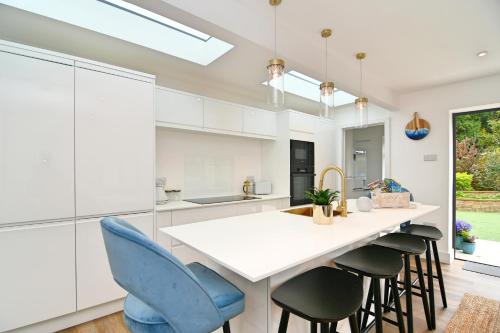 a kitchen with white cabinets and blue chairs at South Coast Beach Holiday Home-3 BED-GF-Sleeps 6-Free Parking-Walk to Beach-Private Garden- Families-Professional Groups-Contractors WELCOME in Bournemouth