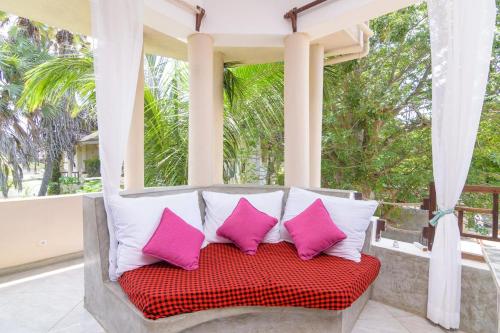 a porch swing with pink and white pillows on it at Couzy stylish stays 3 Bdrm Watamu with Beach access in Watamu