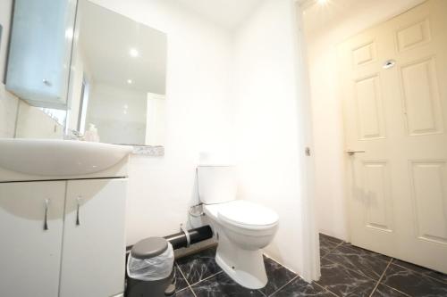 a bathroom with a white toilet and a sink at Airport Comfy Stay in Harmondsworth