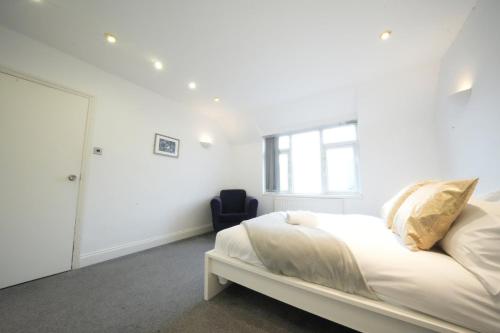 a white bedroom with a bed and a window at Airport Comfy Stay in Harmondsworth