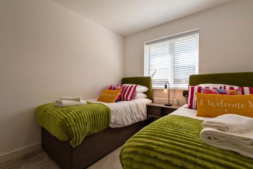 sypialnia z 2 łóżkami i zielonymi kocami w obiekcie Pet friendly house by KBS StayHub Short Lets & Serviced Accommodation Innsworth with parking w mieście Down Hatherley