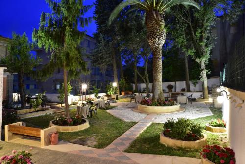 a courtyard with tables and palm trees at night at San Gabriele in Loreto