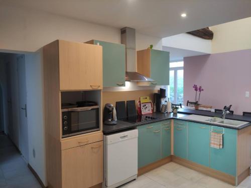a kitchen with blue cabinets and a microwave at Maison Proche Gare in Neufchâteau